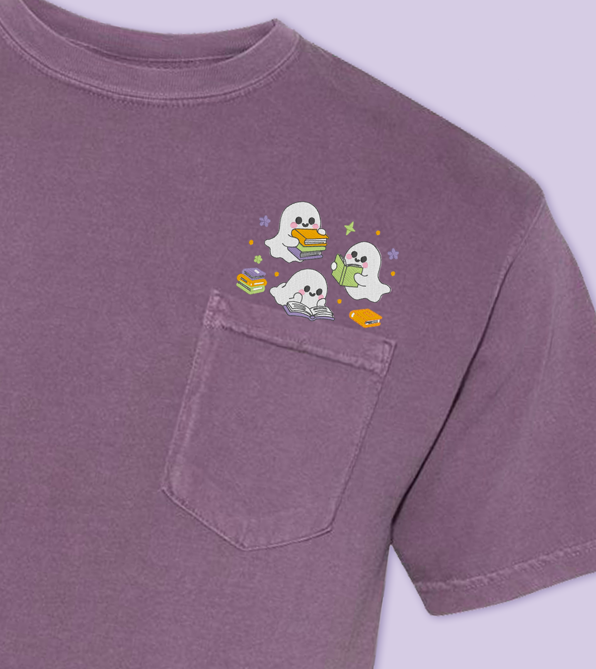 A dark purple short-sleeve pocket t-shirt featuring a small embroidered cartoon graphic of a three ghosts reading peeking out of the chest pocket, set against a matching light purple background.